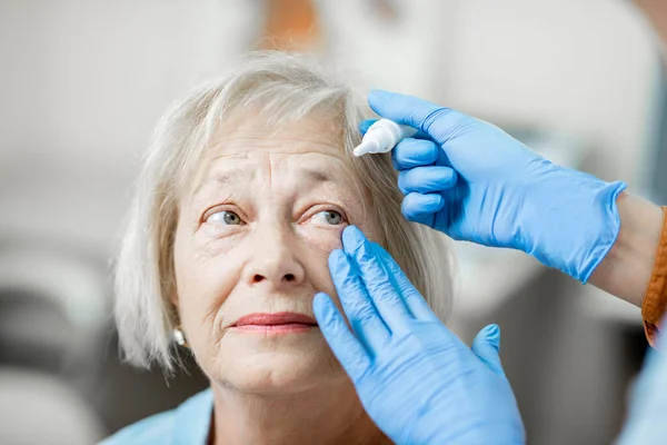 Médico pingando colírio nos olhos de um paciente sênior — Fotografia de Stock