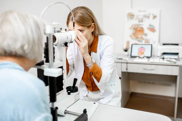 Офтальмолог осматривает глаза под микроскопом — стоковое фото