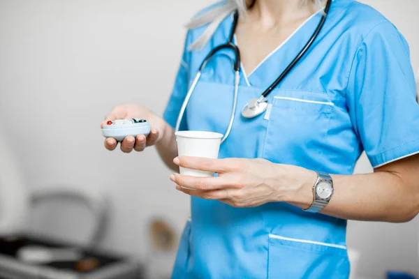 Enfermeira com pillbox e um copo de água — Fotografia de Stock