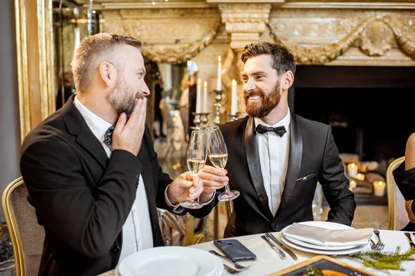 Şık giyimli iki adam yeni yıl arifesinde şenlikli bir yemek yiyorlar. — Stok fotoğraf
