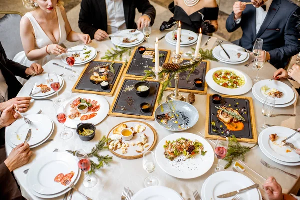 Pessoas elegantemente vestidas tendo um jantar festivo dentro de casa — Fotografia de Stock