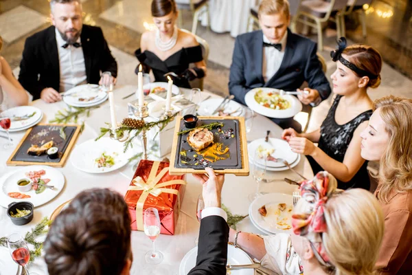 Zarif giyimli insanlar içeride şenlikli bir akşam yemeği yiyor. — Stok fotoğraf