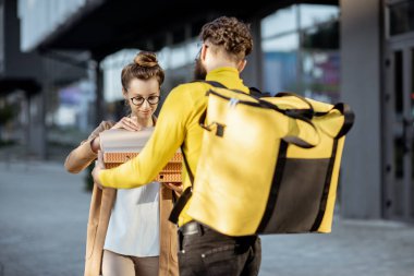 Dışarıdaki genç bir kadına pizza getiren bir adam.