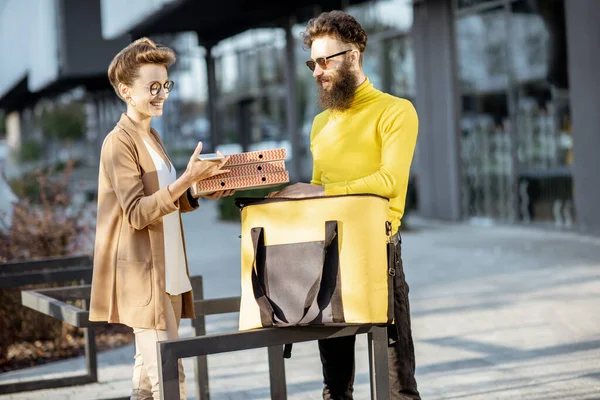 Mannen levererar pizza till en ung kvinna klient — Stockfoto