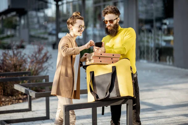 Мужчина доставляет пиццу молодой женщине-клиенту — стоковое фото