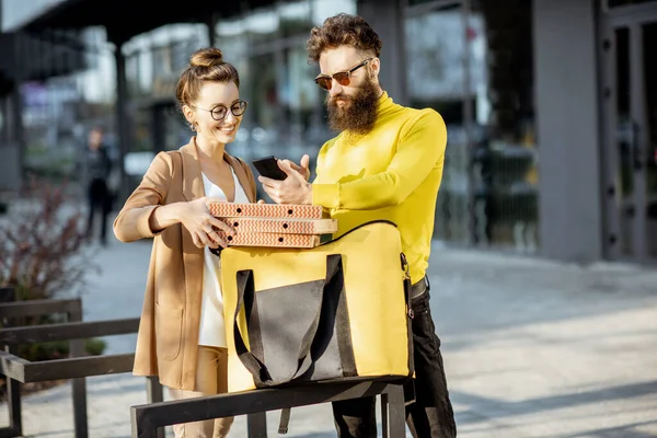 Genç bir kadın müşteriye pizza getiren bir adam. — Stok fotoğraf