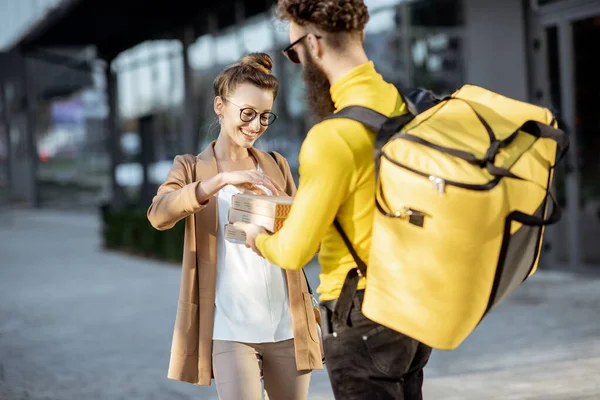 Man leveren pizza aan een jonge vrouw buiten — Stockfoto