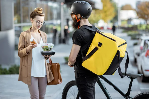 Mensajero entregando comida a una mujer de negocios al aire libre — Foto de Stock