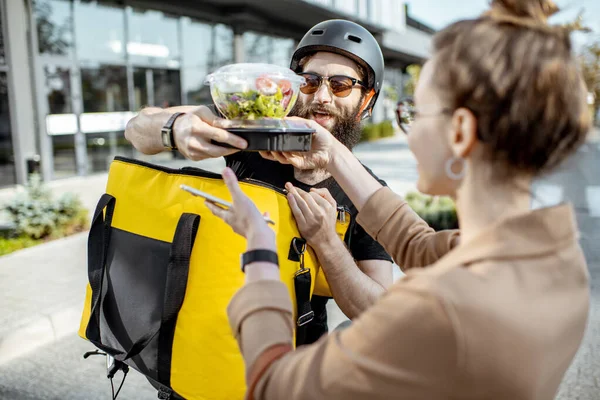 Mensajero entregando comida a una mujer de negocios al aire libre — Foto de Stock