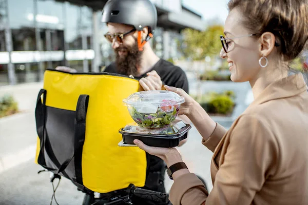 Mensajero entregando comida a una mujer de negocios al aire libre — Foto de Stock