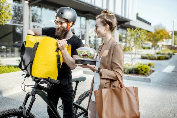 Mensajero entregando comida a una mujer de negocios al aire libre — Foto de Stock