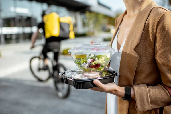 Koerier levert voedsel aan een zakenvrouw — Stockfoto