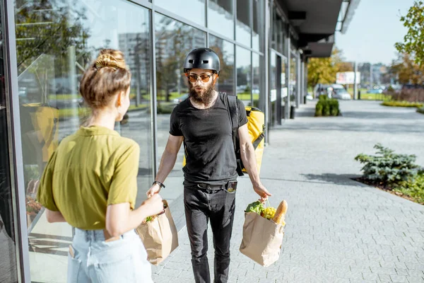 Correio entregando alimentos frescos para uma jovem mulher — Fotografia de Stock