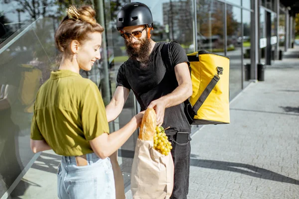 Correio entregando alimentos frescos para uma jovem mulher — Fotografia de Stock