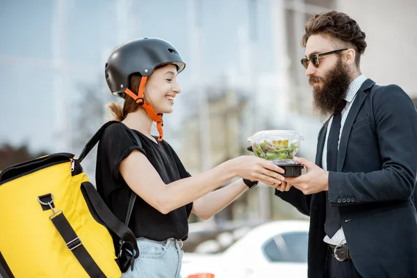 Female courier delivering food to an office worker — Stock Photo, Image