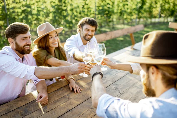 Vrienden die wijn drinken aan de eettafel op de wijngaard — Stockfoto