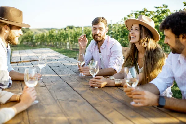 Vrienden die wijn drinken aan de eettafel op de wijngaard — Stockfoto