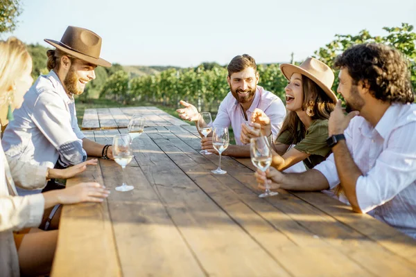 Vrienden die wijn drinken aan de eettafel op de wijngaard — Stockfoto