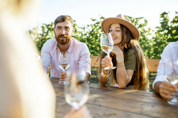 Друзья пьют вино за обеденным столом на винограднике — стоковое фото