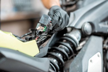 Elektrikçi motorsiklet kablolarını tamir ediyor.