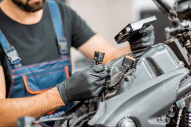 Elektrikçi motorsiklet kablolarını tamir ediyor.