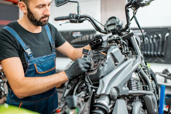 Elektrikçi motorsiklet kablolarını tamir ediyor.