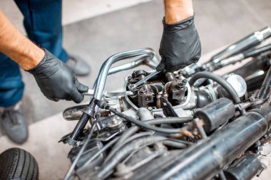 Atölyede motorunu tamir eden bir işçi.