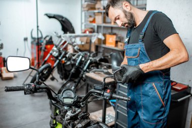 Tamirci motorsikleti tamir ediyor ya da ayarlıyor