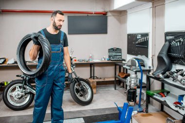 Atölyede motosiklet lastiği olan bir servis çalışanı.