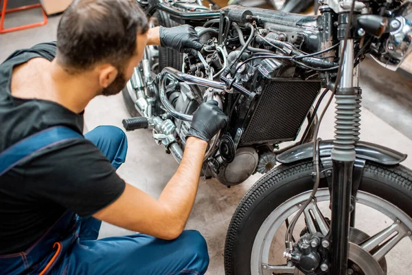 Trabajador reparando motor de motocicleta en el taller — Foto de Stock