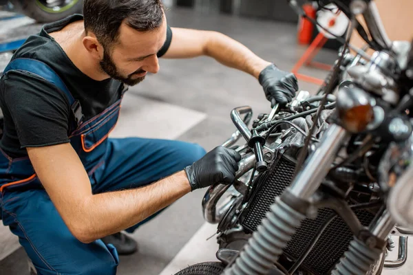 Trabajador reparando motor de motocicleta en el taller — Foto de Stock