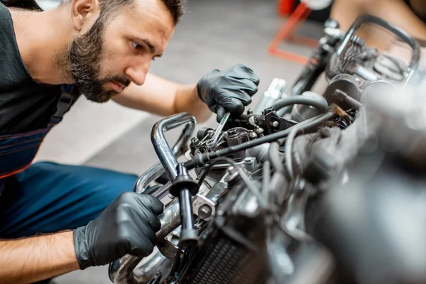 Trabajador reparando motor de motocicleta en el taller — Foto de Stock