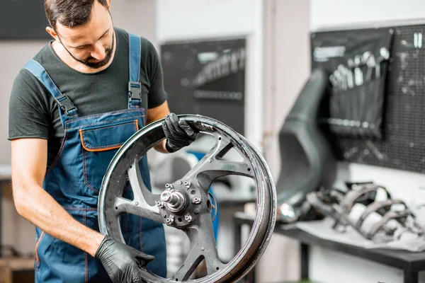 Trabajador cambiando un neumático de motocicleta — Foto de Stock