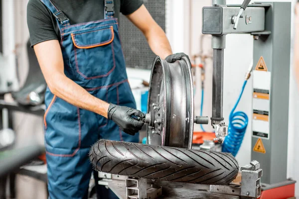 Trabajador cambiando un neumático de motocicleta — Foto de Stock