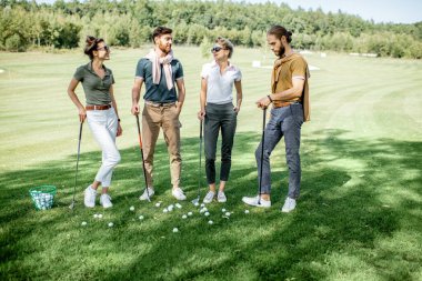 Golf sahasında oyun ekipmanları olan arkadaşlar.