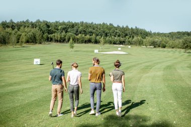 Golf sahasında oyun ekipmanları olan arkadaşlar.