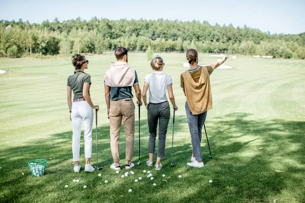 Golf sahasında oyun ekipmanları olan arkadaşlar.