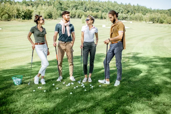 Golf sahasında oyun ekipmanları olan arkadaşlar.