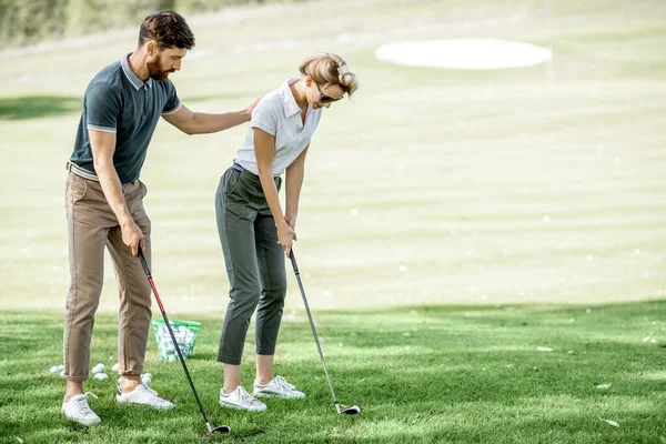 Erkek eğitmeni olan bir kadın golf oynuyor. — Stok fotoğraf