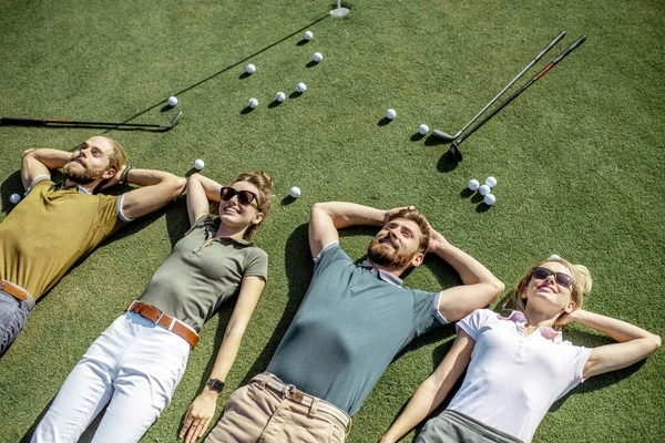 Amigos deitados no campo de golfe — Fotografia de Stock