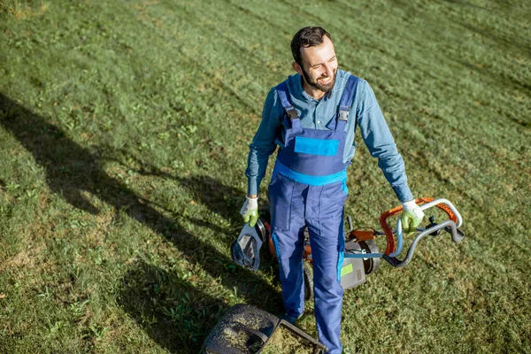 Gardener working with lawn mower on the backyard — Stock Photo, Image