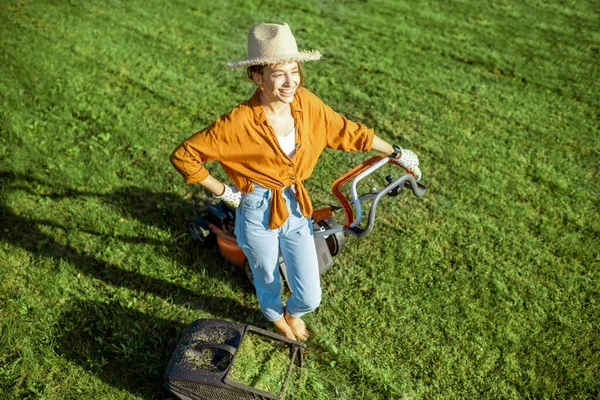 Kvinna med gräsklippare på bakgården — Stockfoto