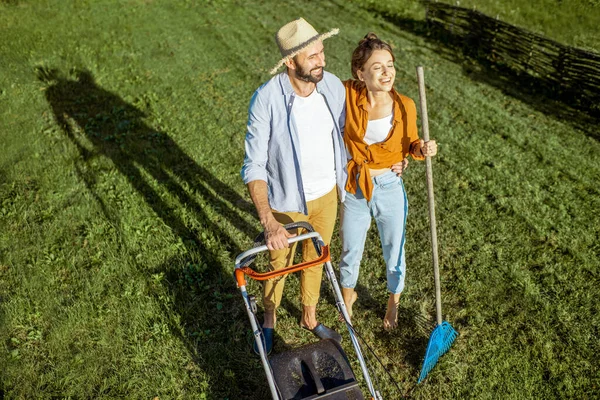 Мужчина и женщина чистят зеленый газон — стоковое фото