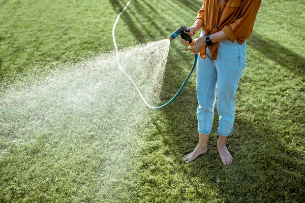 Woman watering green lawn