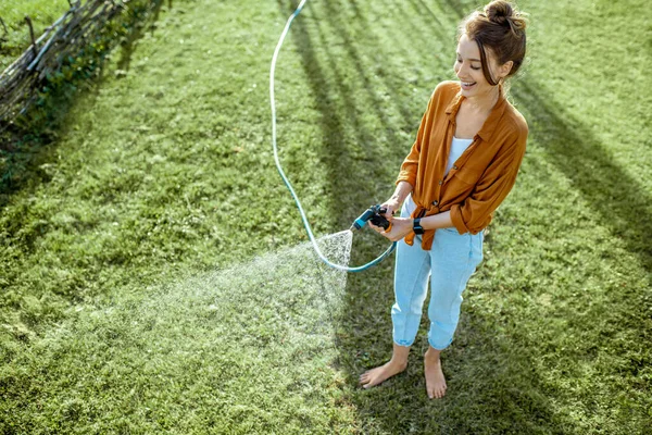 緑の芝生を散水女性 — ストック写真