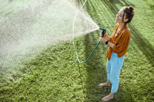 Zöld gyepet locsoló nő — Stock Fotó