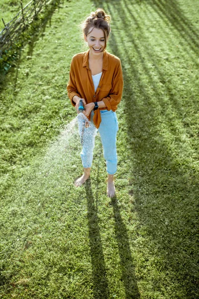 Femme arrosage pelouse verte — Photo
