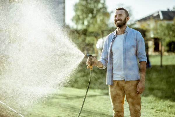 Uomo irrigazione prato verde sul cortile — Foto Stock