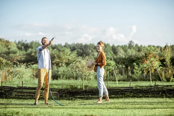 Homme et femme arrosant la pelouse verte sur le jardin — Photo