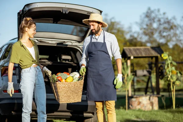 Férfi és nő friss zöldségekkel az autó közelében, vidéken — Stock Fotó